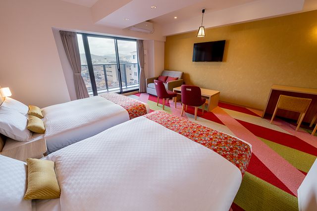 The room has colorful touches all over! The pillows, bedspreads, and lamps all have a playful style.  The colorful cushion provides seating.