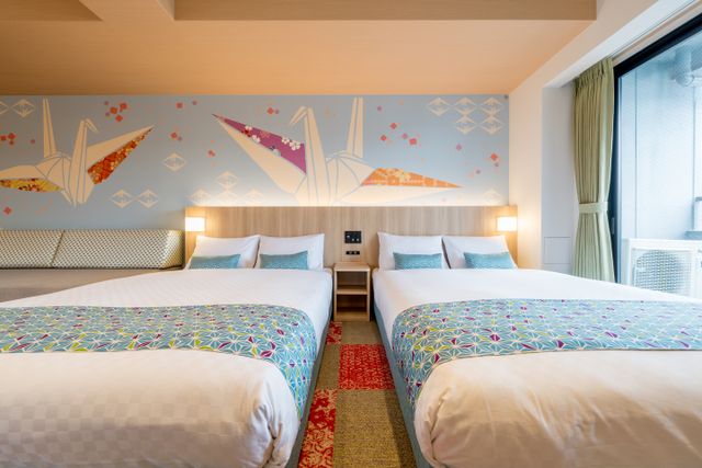 This room has two Double beds and a sofa bed. The colorful theme is taken from the "ORIGAMI" pattern on the wall.
